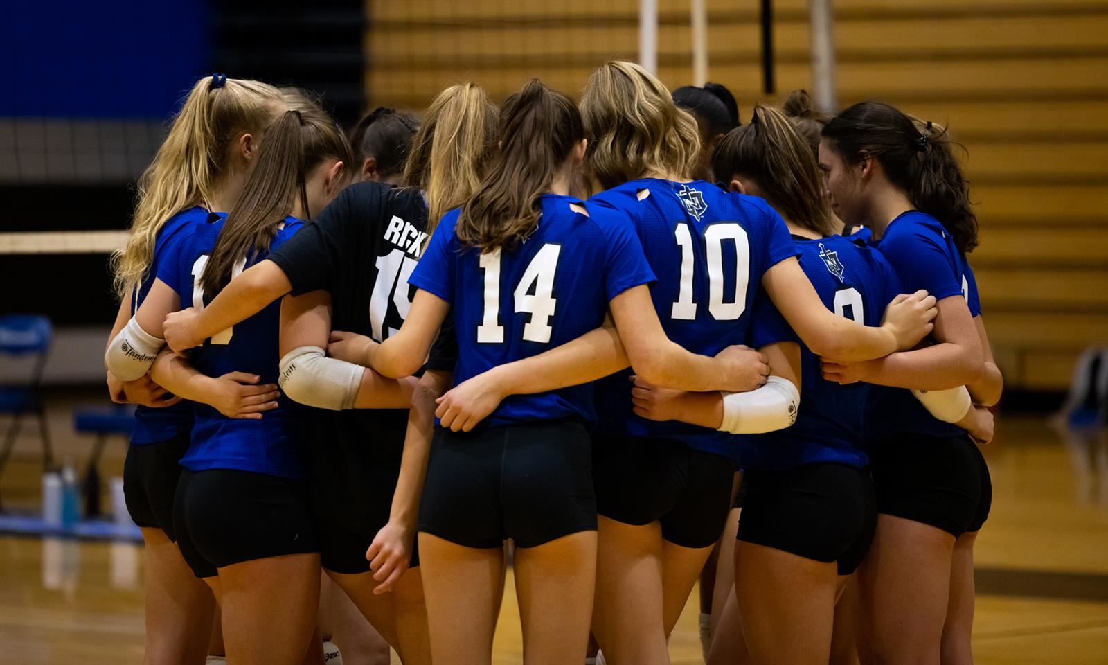 The NHS volleyball team huddles together during a game